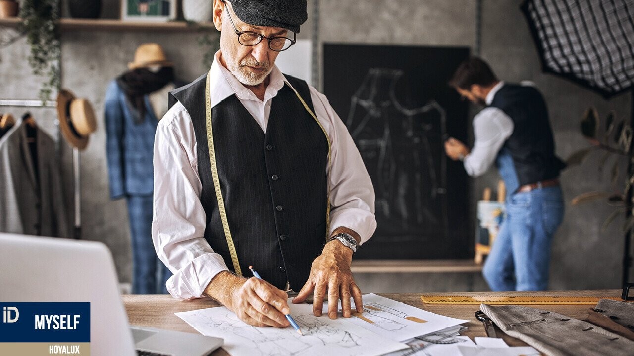 The picture shows an elderly male wearing glasses, noting something in a tailor shop.