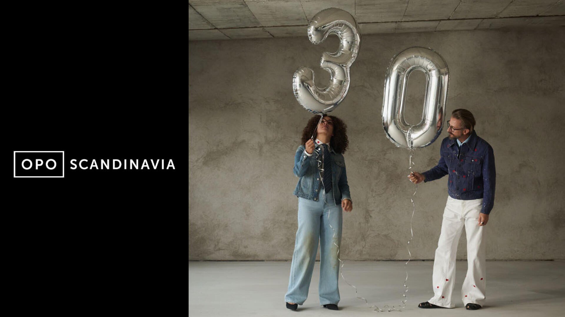 Zwei Personen in Jeans-Outfits halten große silberne Luftballons in Form der Zahl 30 und stehen in einem minimalistischen Raum. Auf der linken Seite des Bildes ist das Logo von OPO SCANDINAVIA auf schwarzem Hintergrund zu sehen.