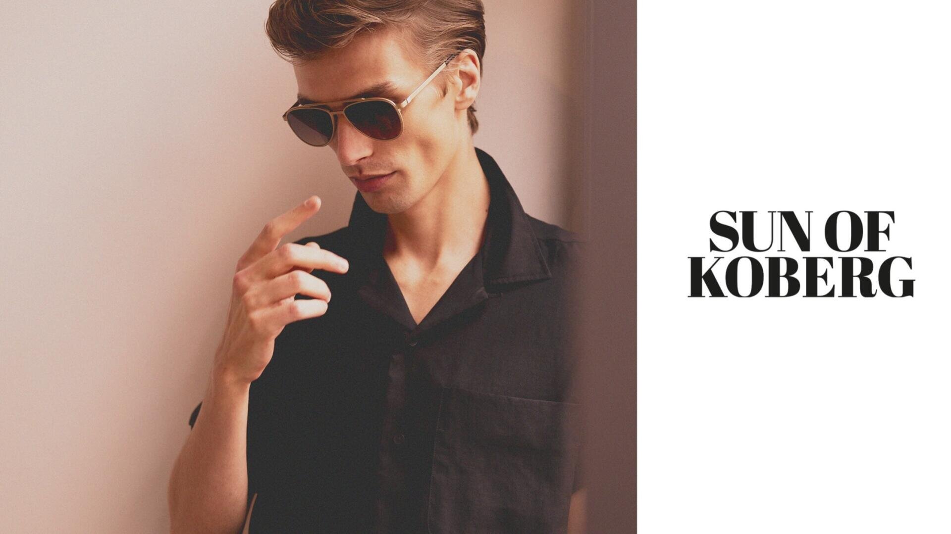 A man in sunglasses and a black shirt stands against a light background, looking down and touching his fingers. Text on the right reads SUN OF KOBERG in bold black letters.