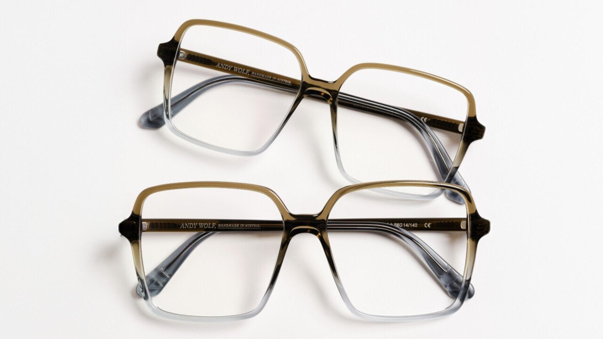 Two pairs of rectangular eyeglasses with brown and clear ombre frames are laid side by side on a white surface, with the temples folded.