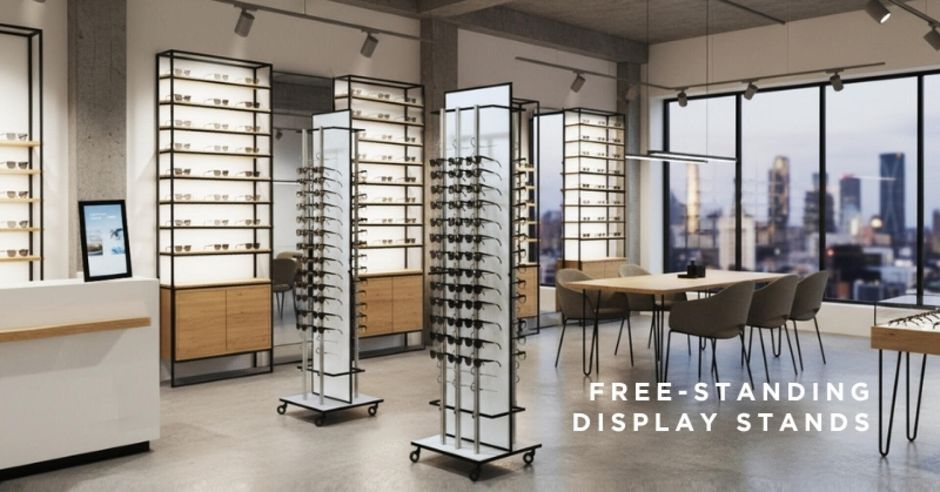 A modern eyewear store interior with free-standing display stands holding glasses, wooden furniture, seating areas, and large windows overlooking a city skyline. Text reads: Free-standing display stands.