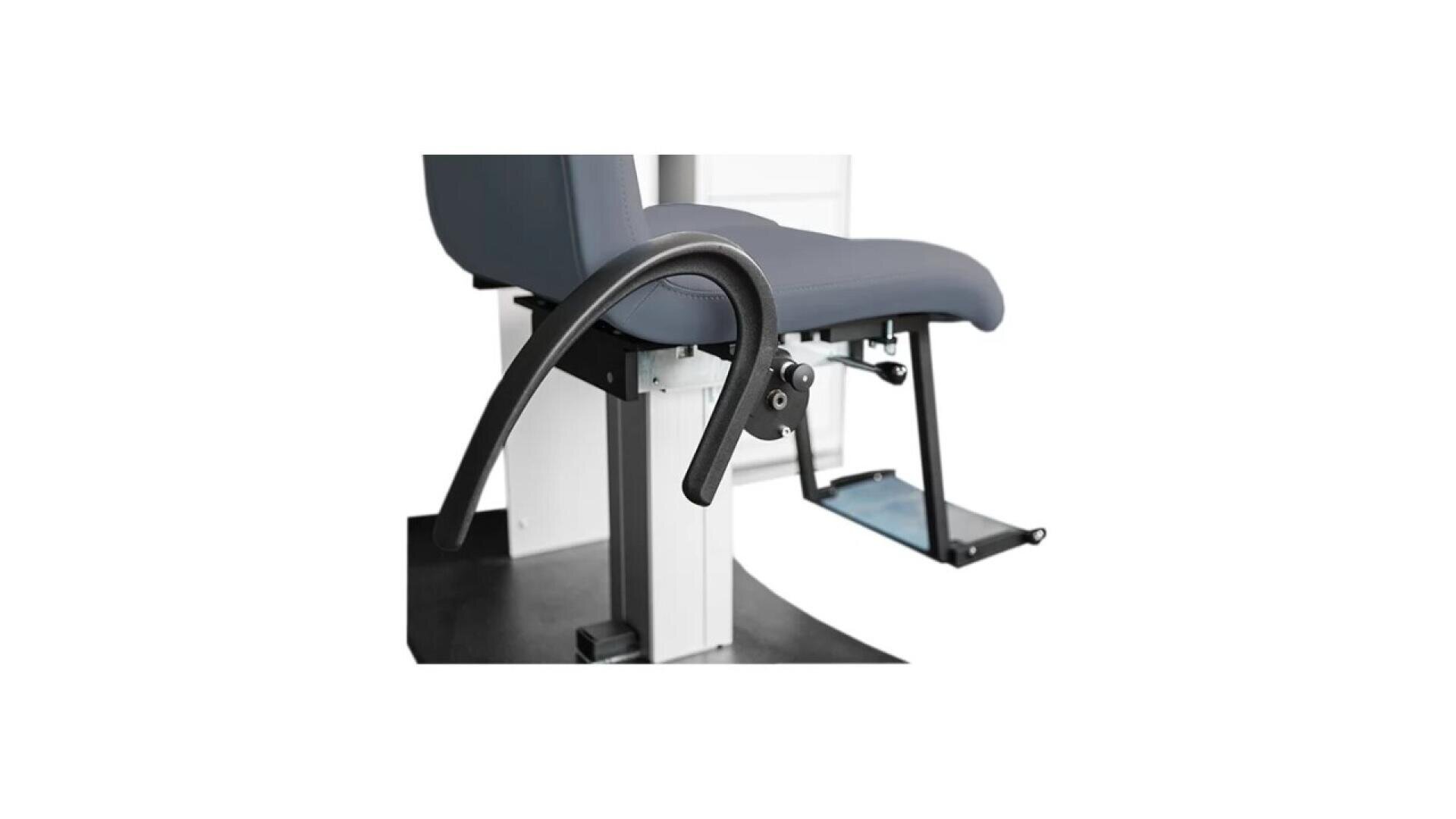 A close-up view of a modern medical chair with a curved black armrest, blue-gray cushioned seat, adjustable metal footrest, and sturdy white base.