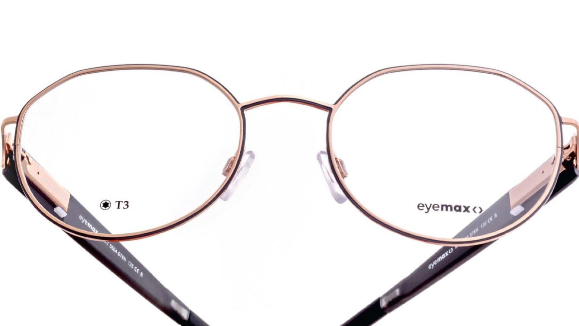 Eine goldene, runde Brille mit dünnem Metallrahmen, klaren Gläsern und schwarzen Bügeln, die vor einem weißen Hintergrund präsentiert wird. Die Gläser haben kleine T3 und eyemax Etiketten.