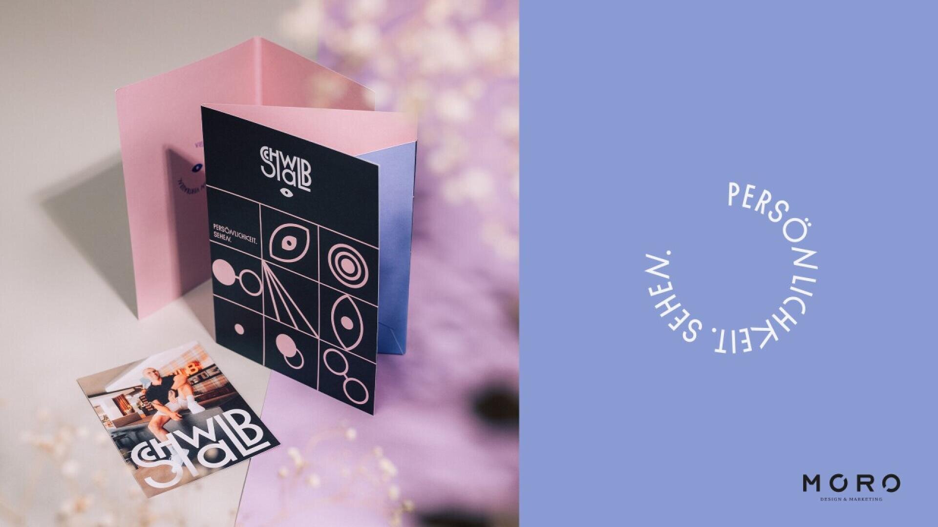 A navy and pink folded card with abstract white designs stands open beside a square photo of a woman indoors. The background is lavender. On the right, white circular text reads PERSÖNLICHKEIT WESEN above a small MGRO logo.