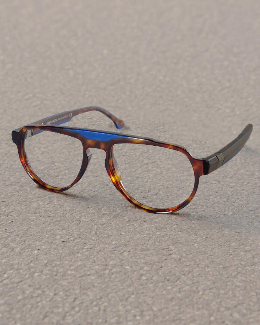 A pair of brown tortoiseshell glasses with round lenses lies in natural light on a textured gray surface, possibly a sidewalk.