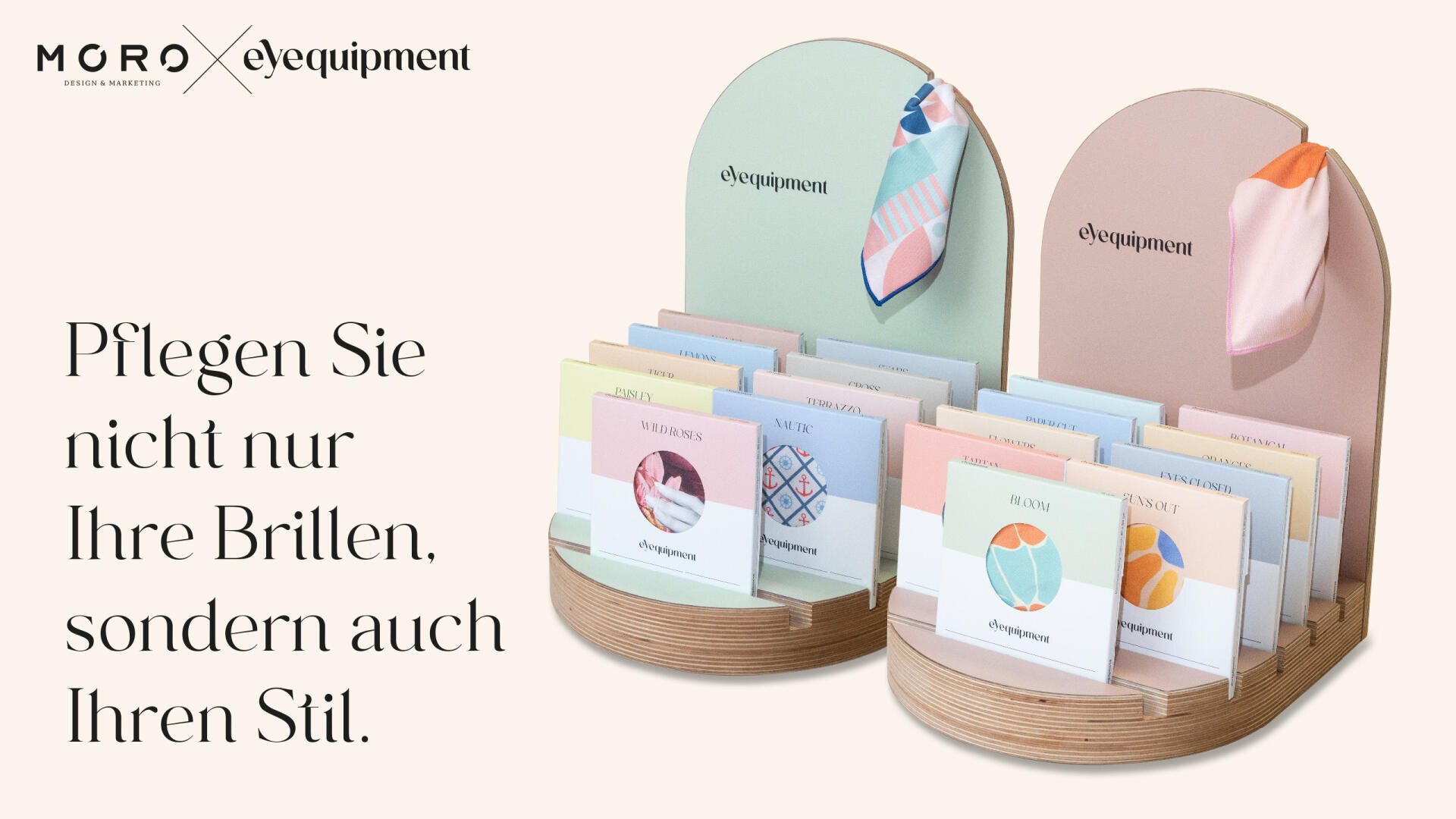Zwei pastellfarbene Präsentationsständer mit Brillenputztüchern in farbenfroher Verpackung. Der deutsche Text lautet: Pflegen Sie nicht nur Ihre Brillen, sondern auch Ihren Stil. Die Umgebung ist sauber und minimalistisch.