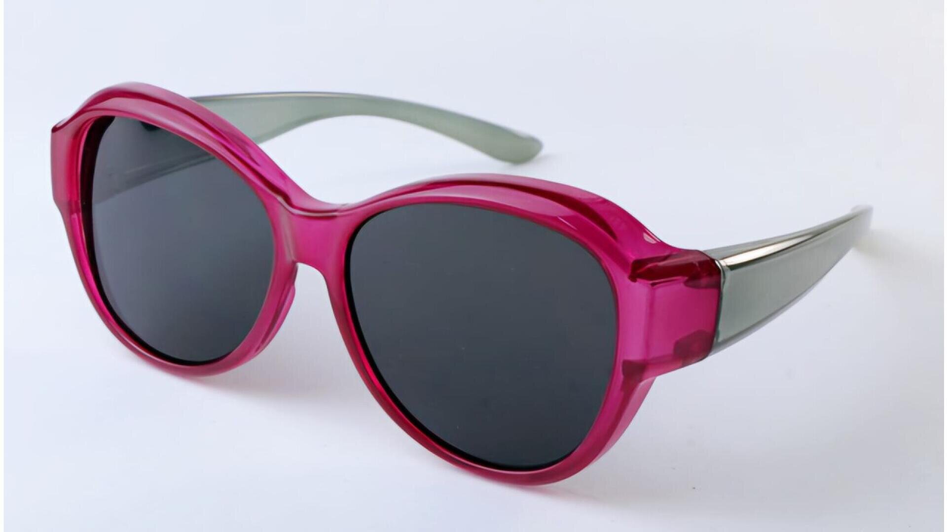 Pink sunglasses with large, round dark lenses and translucent grey arms, displayed on a plain white background.