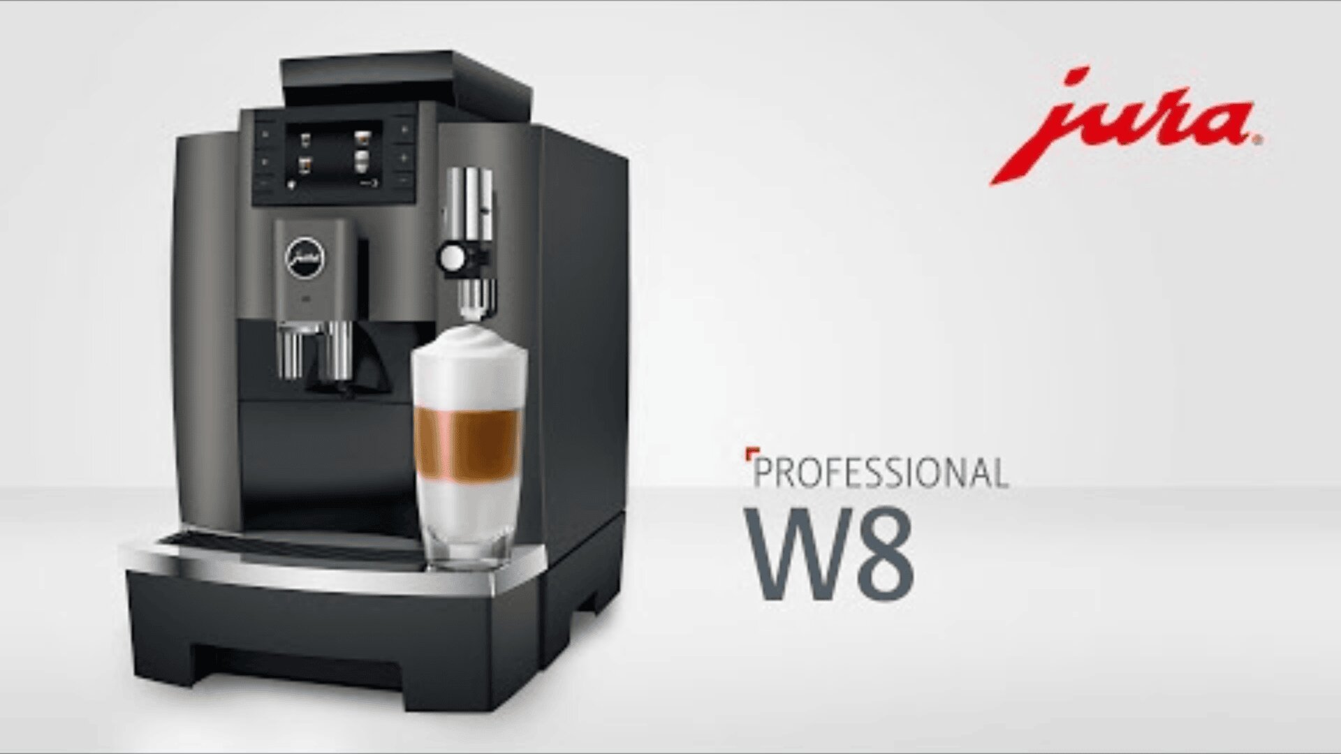 Eine schwarze Jura W8 Professional Kaffeemaschine gießt einen geschichteten Latte in ein Glas. Oben rechts ist das Jura-Logo in Rot zu sehen, neben der Maschine ist der Schriftzug Professional W8 aufgedruckt.