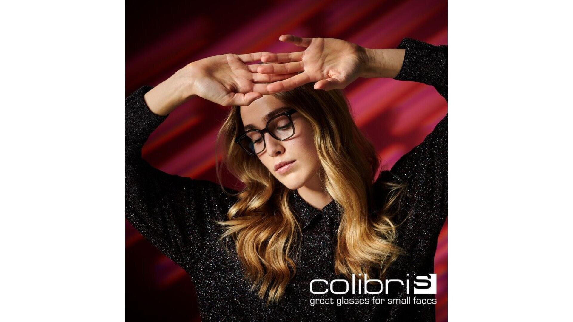 Eine Frau mit langen blonden Haaren und schwarzer Brille posiert mit erhobenen Armen vor einem roten abstrakten Hintergrund. Der Text lautet: colibris große Brille für kleine Gesichter.