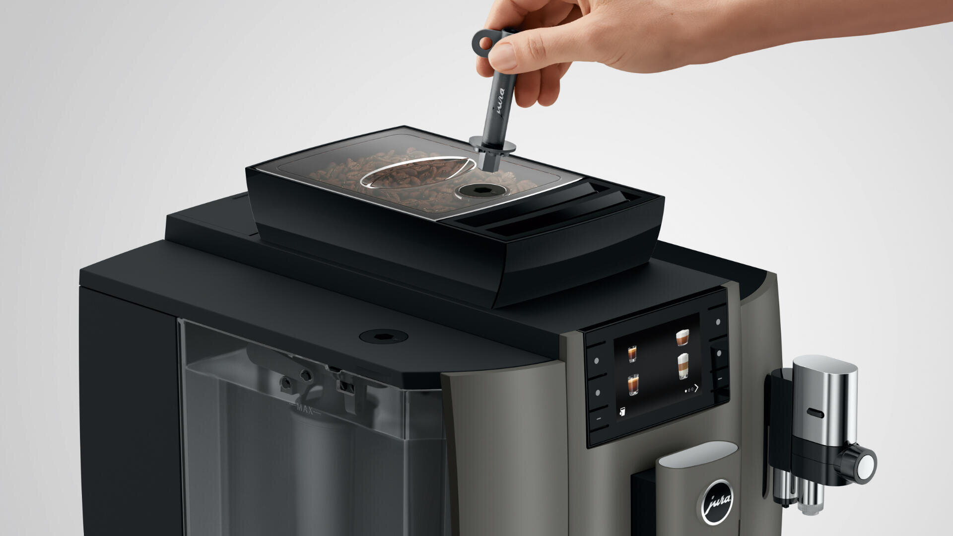 Eine Hand füllt mit einem Messlöffel Kaffeebohnen in das Bohnenfach eines modernen Kaffeevollautomaten mit Digitalanzeige und Wassertank.
