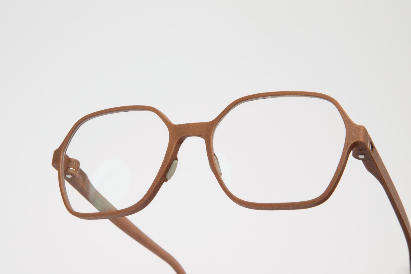 Eine Nahaufnahme einer braunen, rechteckigen Brille mit klaren Gläsern vor einem schlichten weißen Hintergrund.