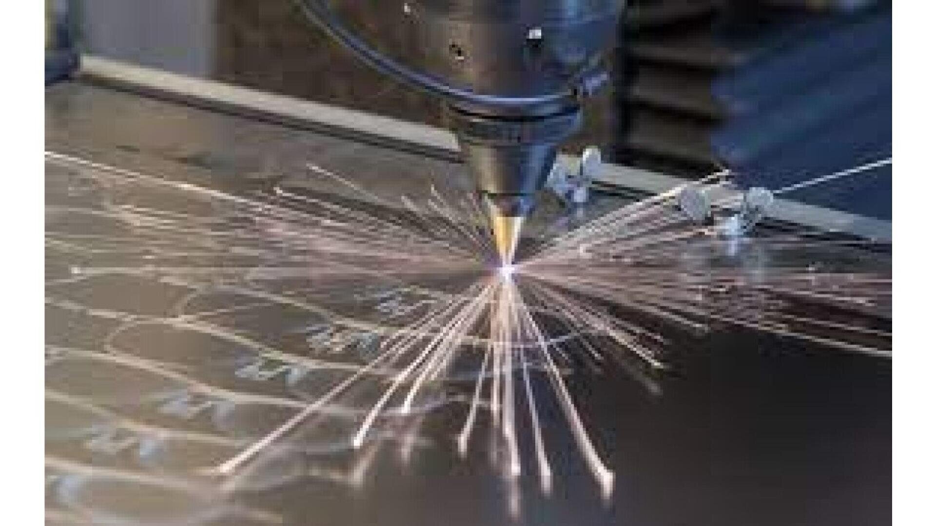 A close-up of a laser cutting machine slicing through a metal sheet, generating bright sparks and precise patterns on the surface.