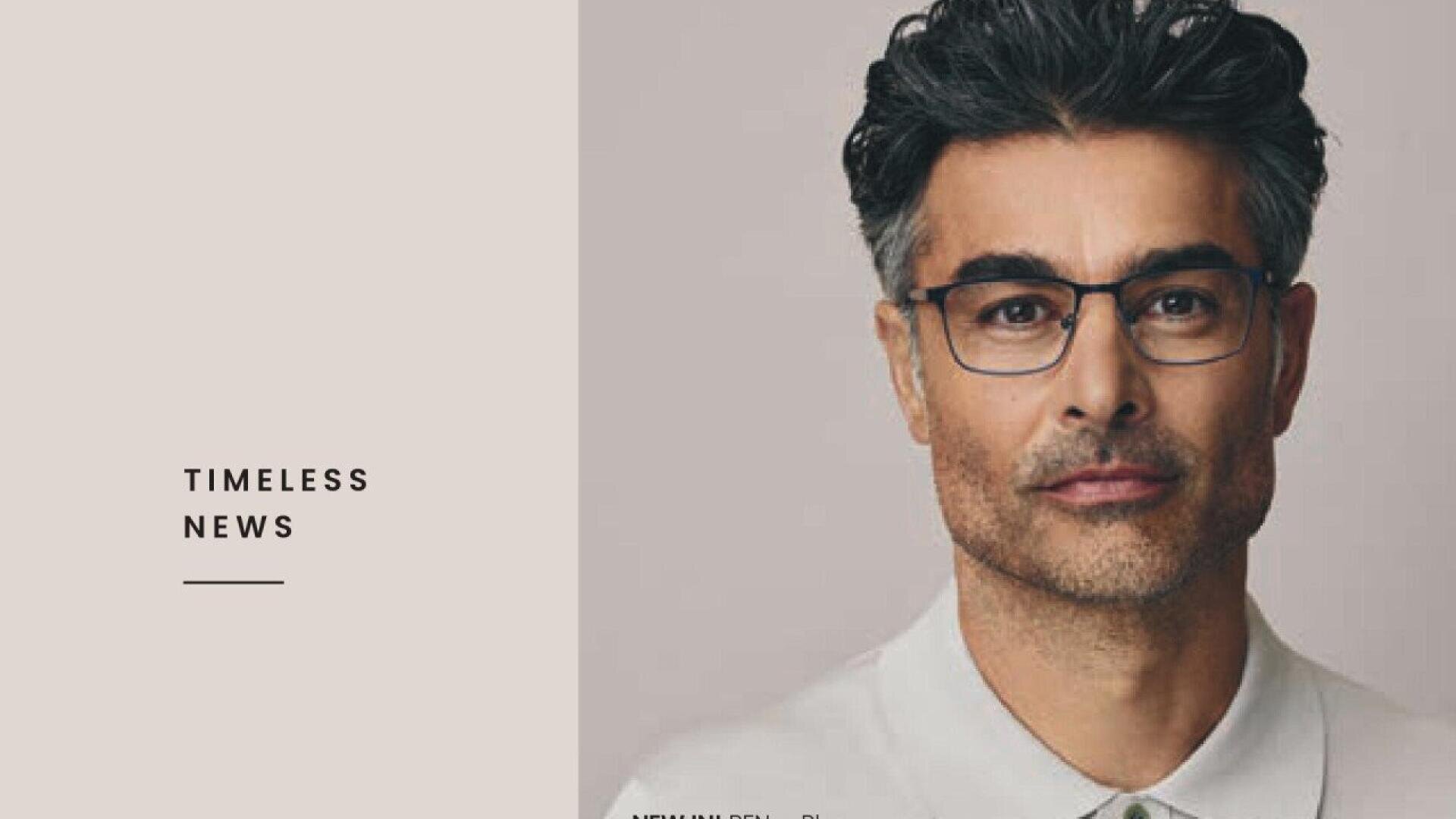 A middle-aged man with gray hair, glasses, and a trimmed beard looks at the camera. He is wearing a white collared shirt. The left side of the image has the text TIMELESS NEWS on a beige background.