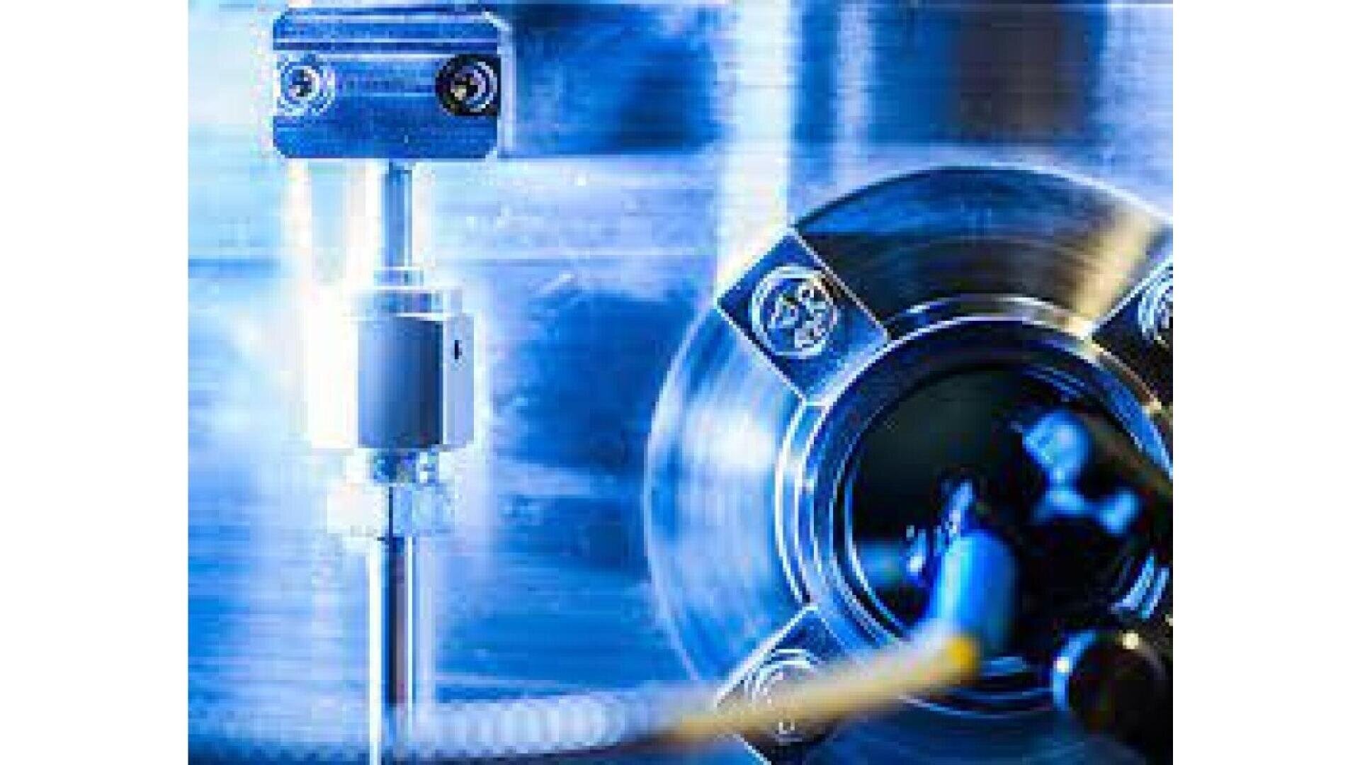 Close-up of industrial machinery with metallic components and bolts, shown in cool blue lighting, highlighting mechanical details and a circular part in the center right of the image.