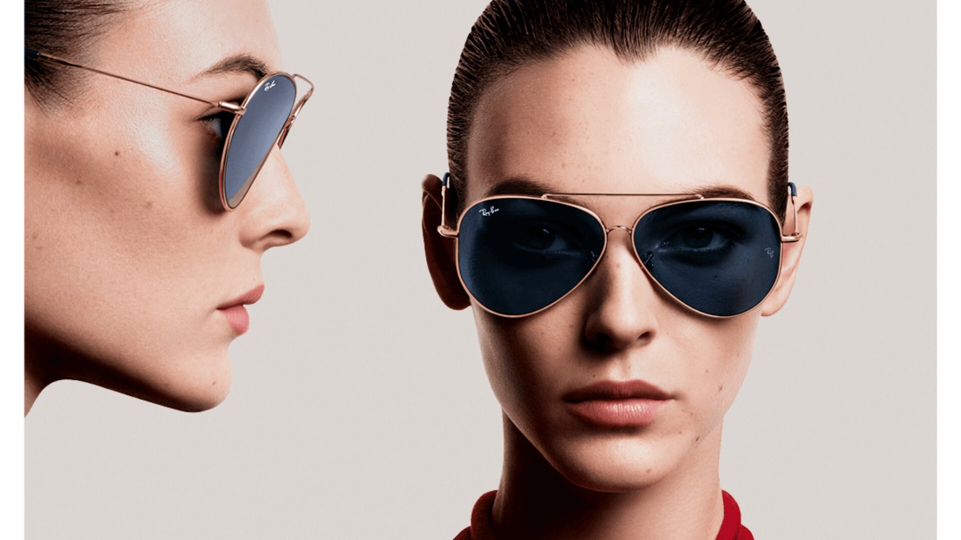 Zwei Frauen mit zurückgegelten Haaren tragen blaue Flieger-Sonnenbrillen, eine mit Blick nach vorne und eine im Profil, beide mit neutralem Gesichtsausdruck vor einem schlichten Hintergrund.