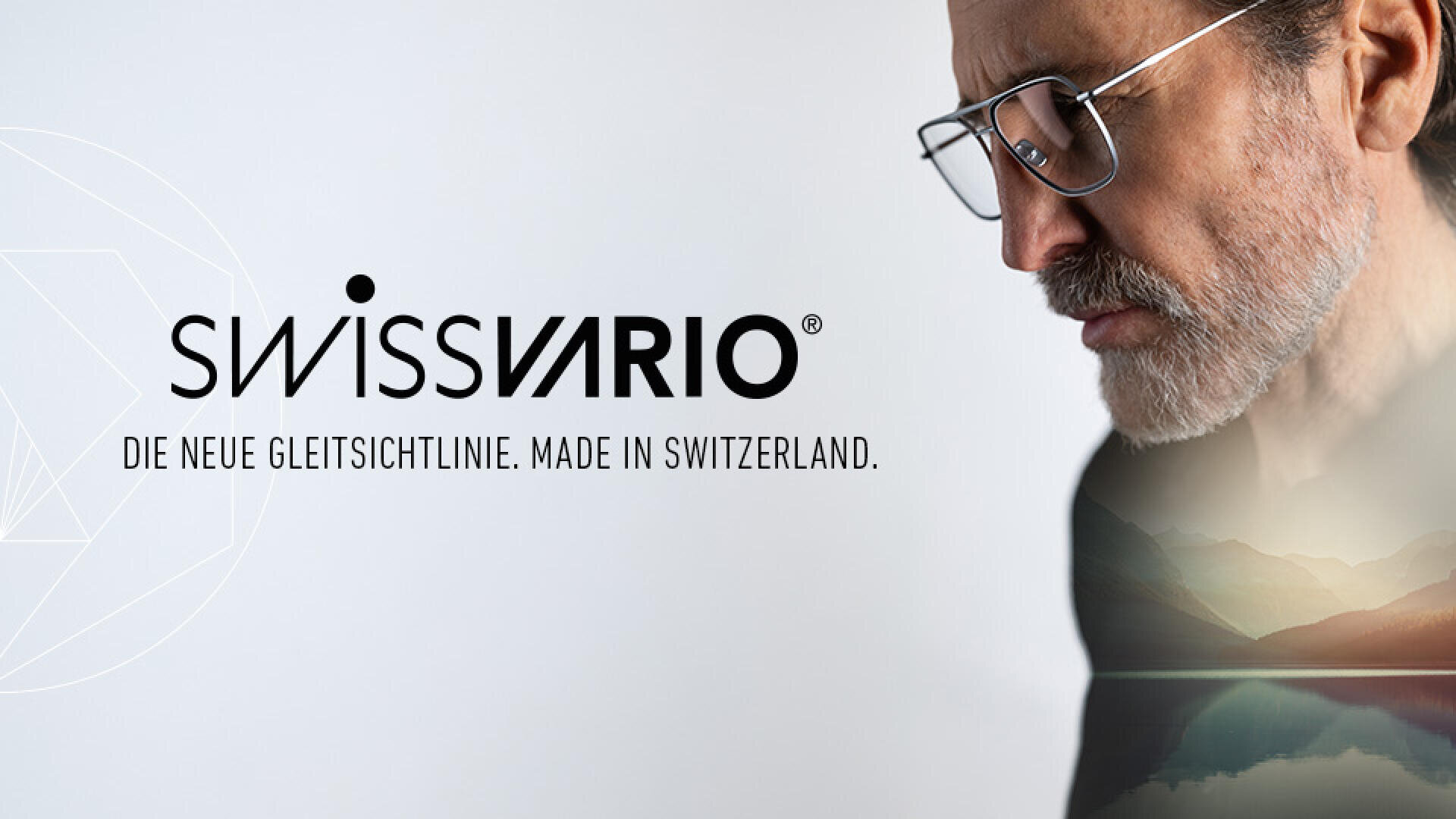 Ein Mann mit Brille blickt nachdenklich nach unten. Neben ihm erscheinen das SwissVario-Logo und der Text Die neue Gleitsichtlinie. Made in Switzerland. erscheinen neben ihm. Seine Silhouette enthält das schwache Bild eines ruhigen Bergsees.