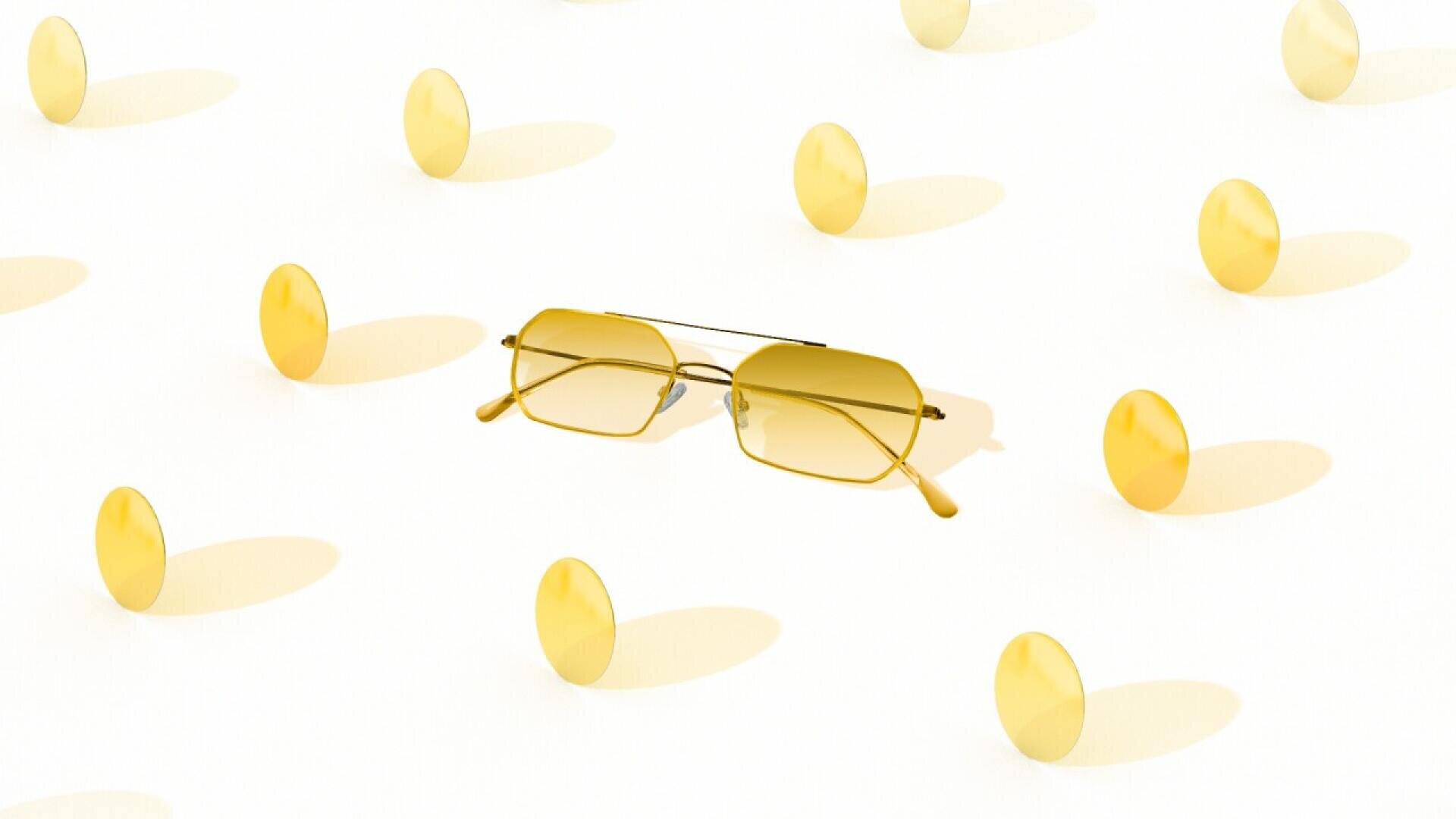 A pair of yellow-tinted sunglasses sits on a white surface, surrounded by evenly spaced, round yellow discs casting soft shadows.