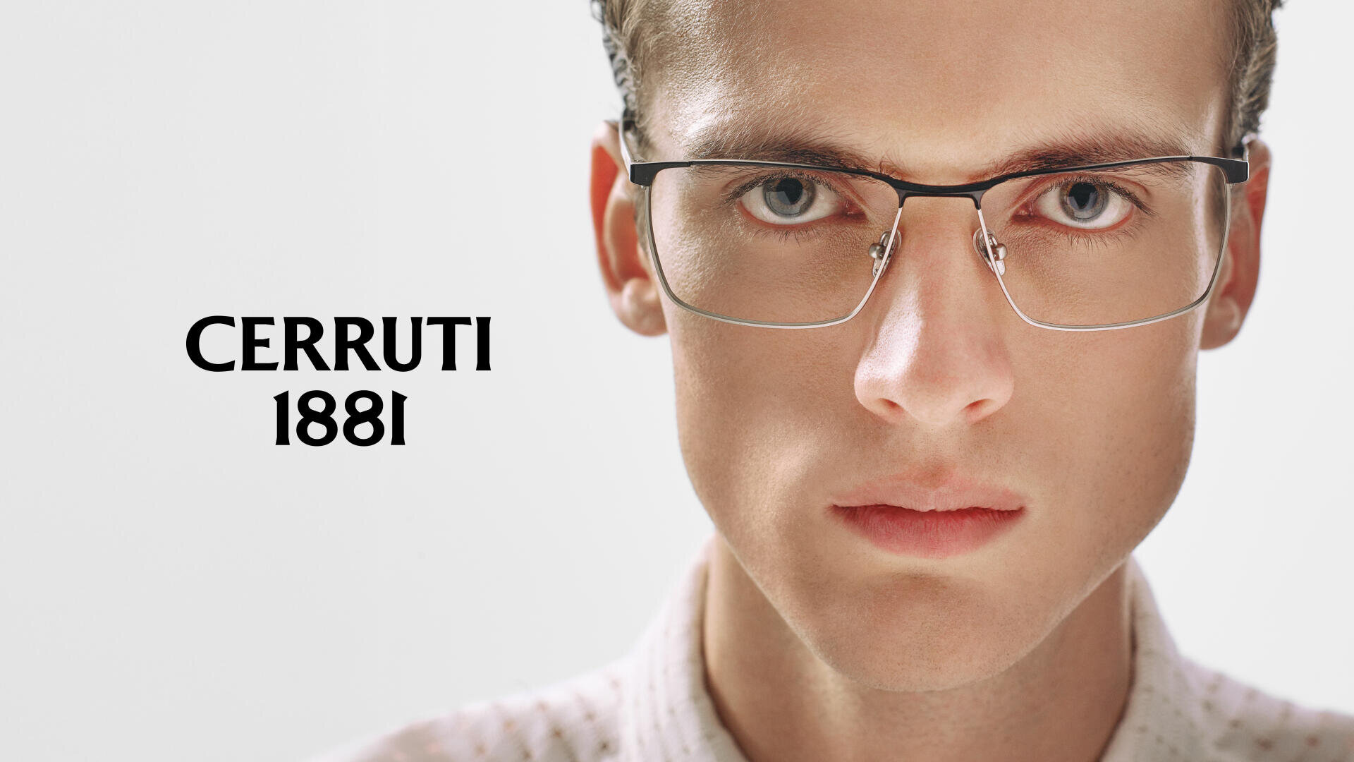 A person wearing rimless eyeglasses and a light-colored shirt stares seriously at the camera. The text CERRUTI 1881 appears in bold black letters to the left on a light background.