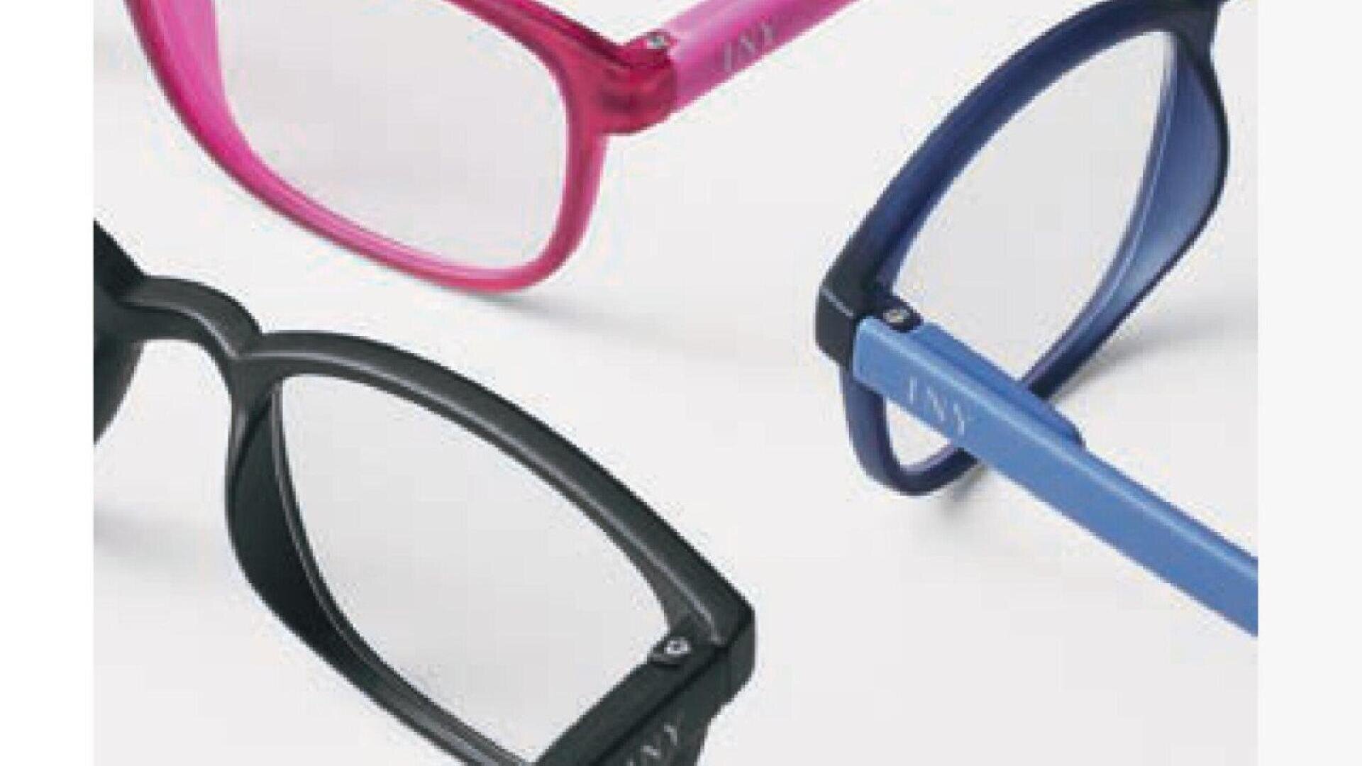 Three pairs of eyeglasses in pink, blue, and black are displayed on a light background, arranged so only part of each frame and one lens are visible.