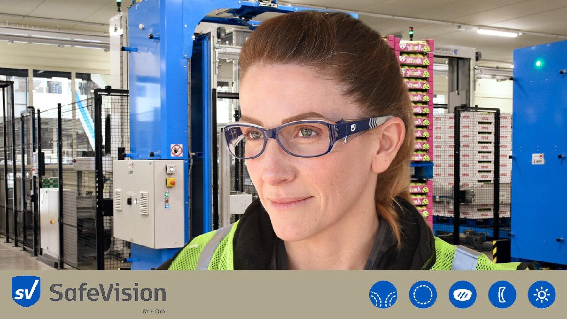 A woman wearing safety glasses and a high-visibility vest stands in a factory setting with machinery in the background. The text SafeVision and several safety-related icons are displayed at the bottom of the image.