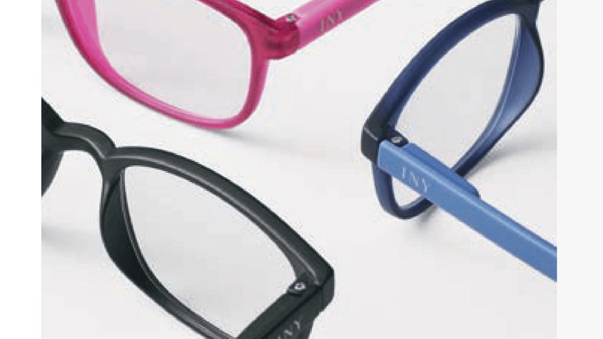 Nahaufnahme von drei Brillen mit Kunststoffrahmen in Schwarz, Rosa und Blau, angeordnet auf einer hellen Fläche.