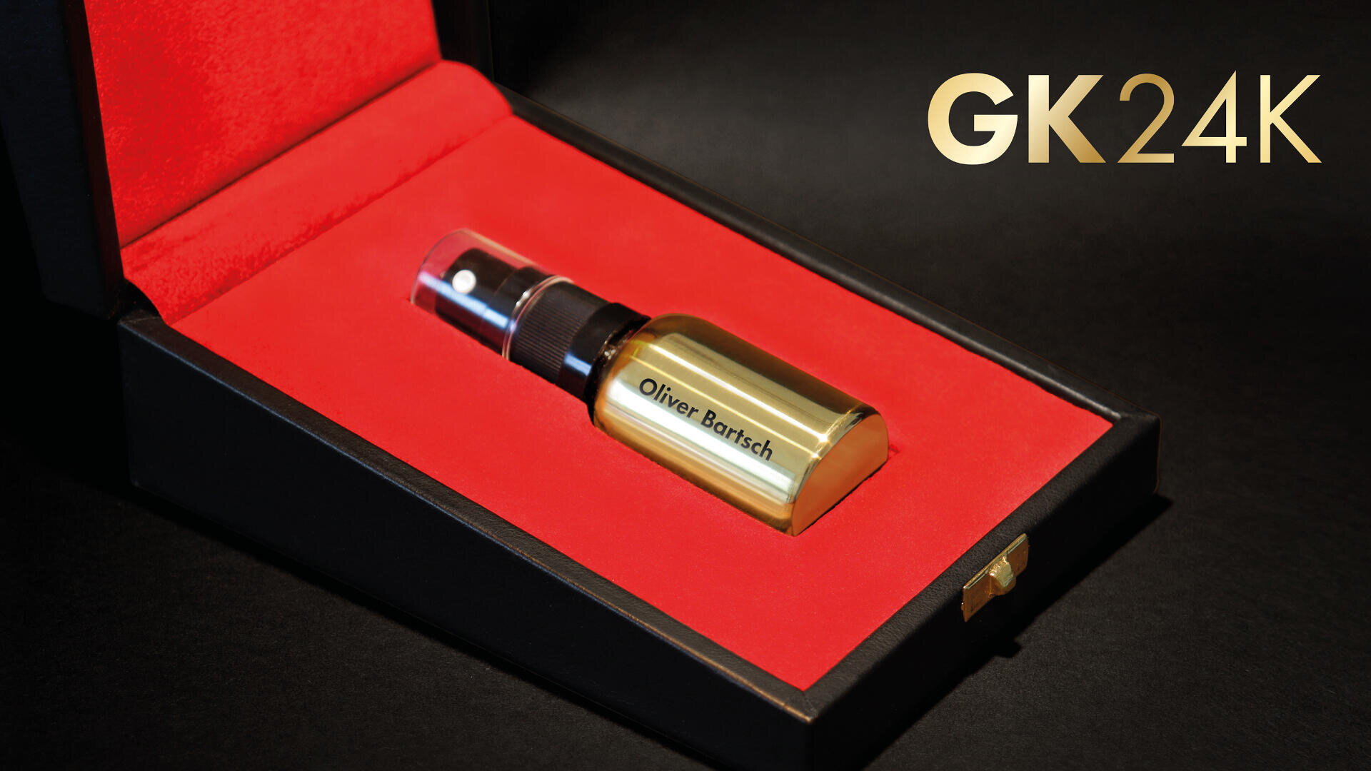 A gold spray bottle labeled Olivier Barsch sits in a black box with red velvet lining. The text GK24K appears in gold lettering on the right side of the image.