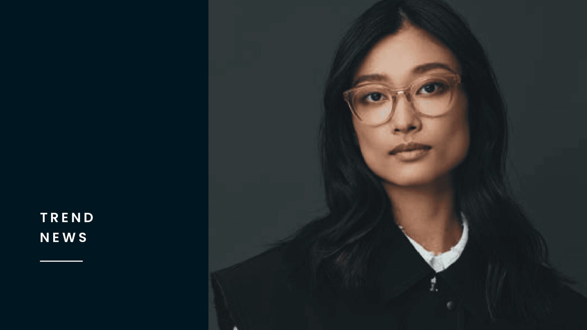Eine Frau mit langen schwarzen Haaren und Brille blickt in die Kamera. Sie trägt eine dunkle Jacke über einem weißen Hemd. Auf der linken Seite erscheint auf einer marineblauen Tafel der Text "TREND NEWS" in weißer Schrift.