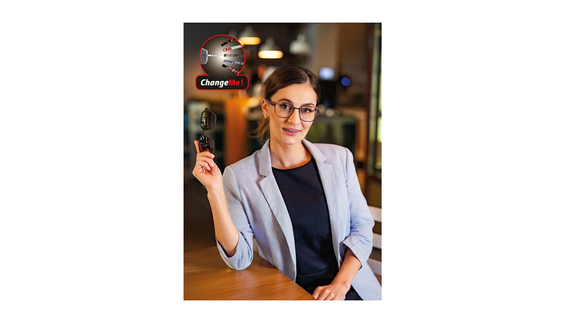 Eine Frau in einem hellen Blazer und mit Brille sitzt an einem Tisch und hält Autoschlüssel in der Hand. In der oberen linken Ecke befindet sich ein roter Kreis mit der Aufschrift Change Me! und der Abbildung eines Schlüssels.