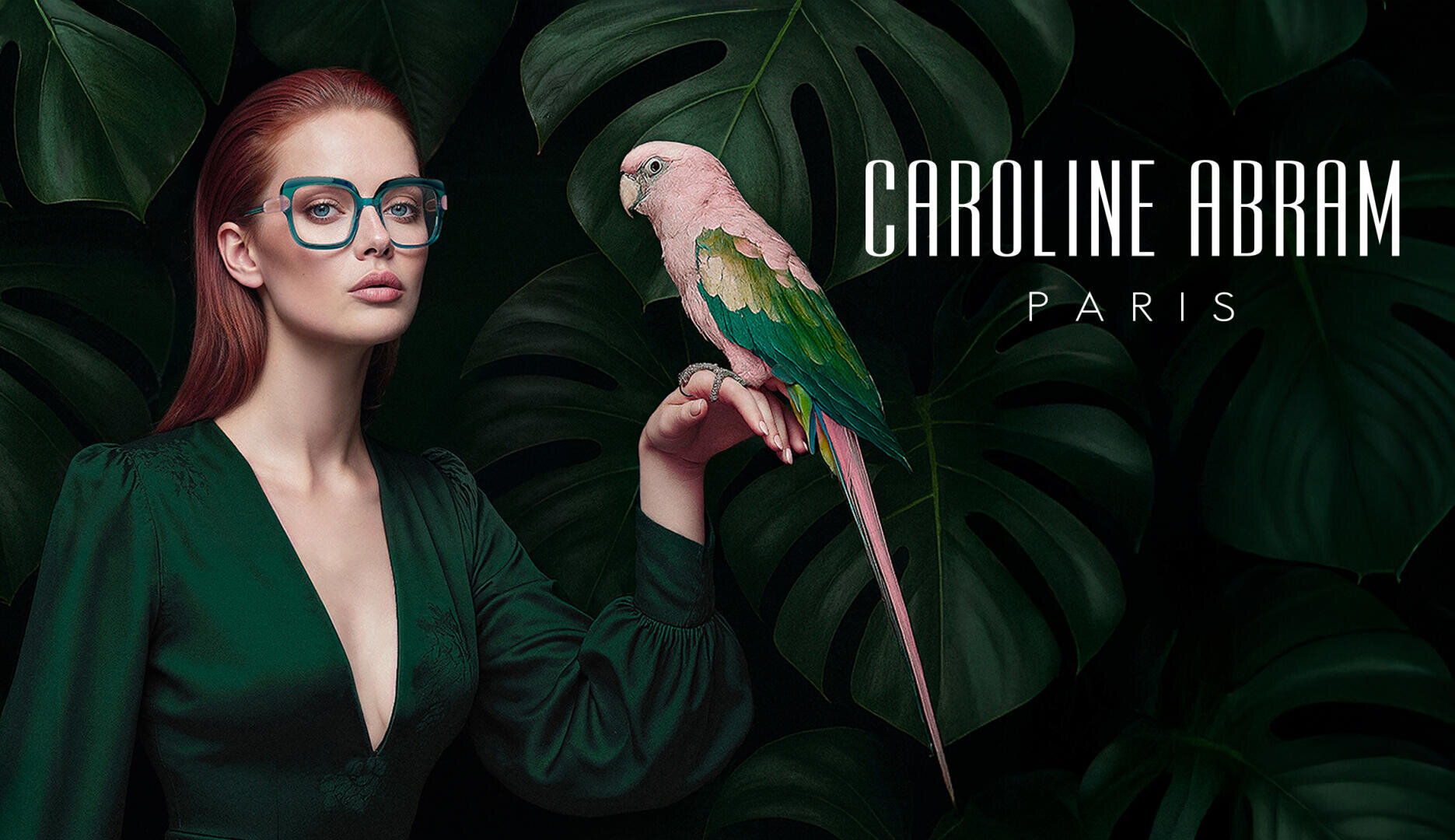Eine Frau in einem tiefgrünen Kleid und mit einer großen Brille hält einen rosa-grünen Papagei und steht vor großen tropischen Blättern. Der Text lautet CAROLINE ABRAM PARIS.