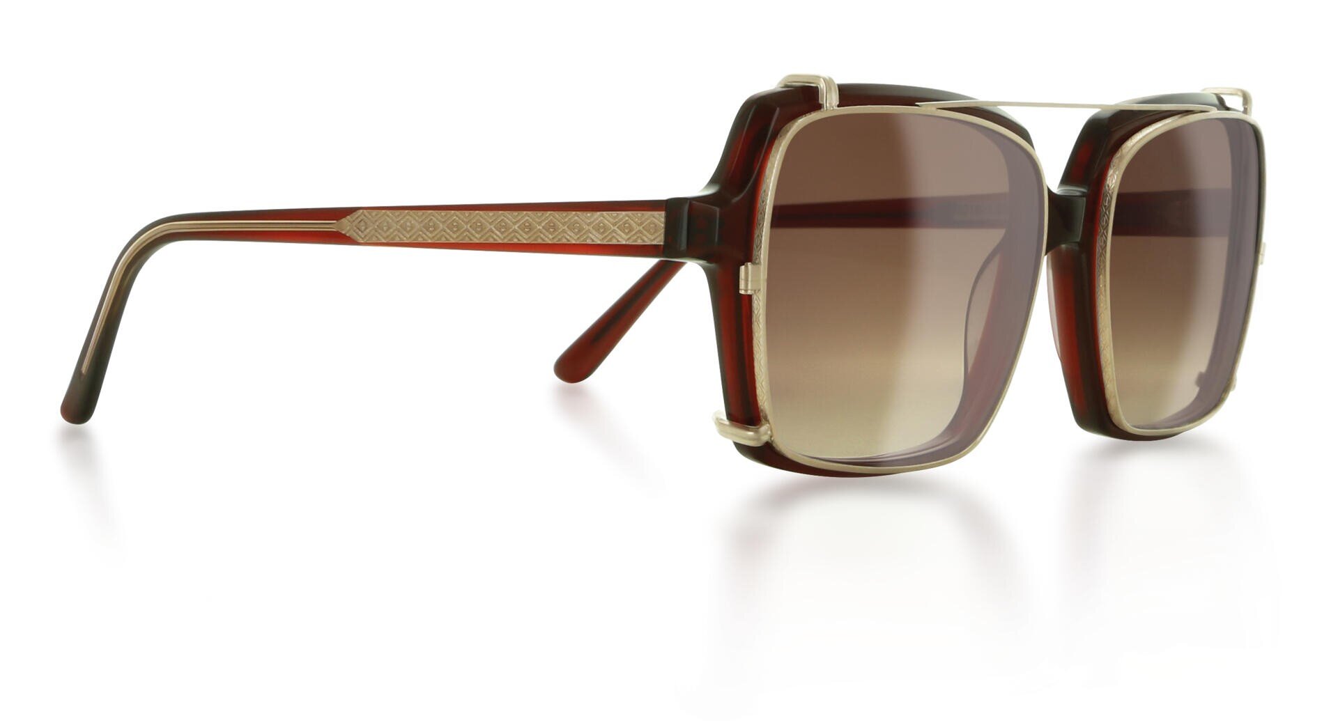 Oversized, square sunglasses with a brown color gradient, thick frame and golden decorations on the temples on a white background.