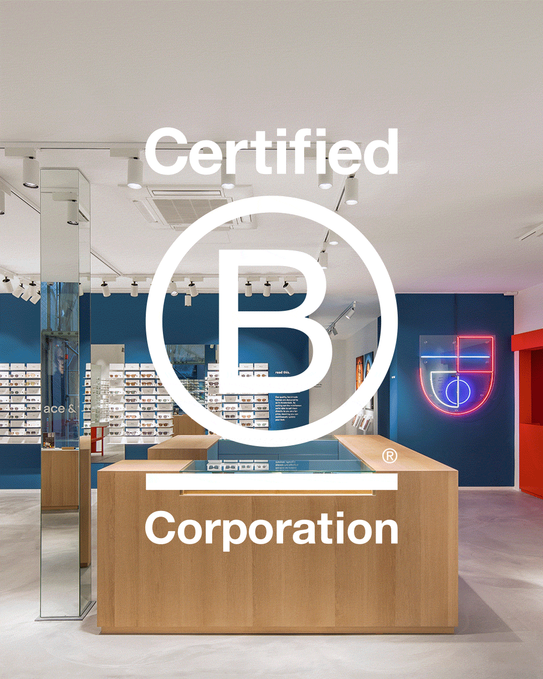 Ein modernes Einzelhandelsgeschäft mit Holztheken, blauen Wänden und einer Leuchtreklame, auf der das Logo der Certified B Corporation in Weiß prangt.