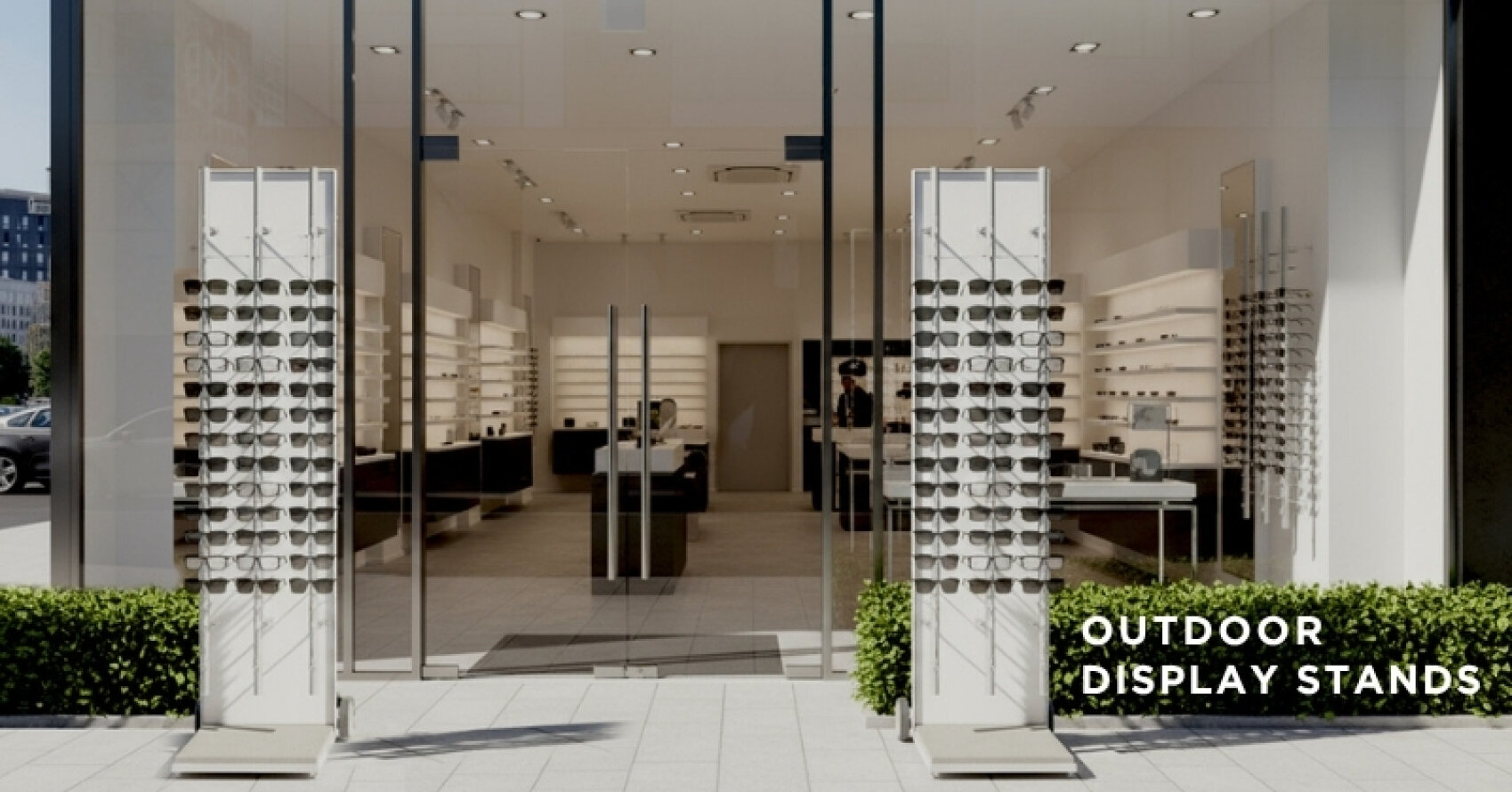 A modern eyewear store with large glass doors and windows, featuring two outdoor display stands with sunglasses. Text on the image reads OUTDOOR DISPLAY STANDS.