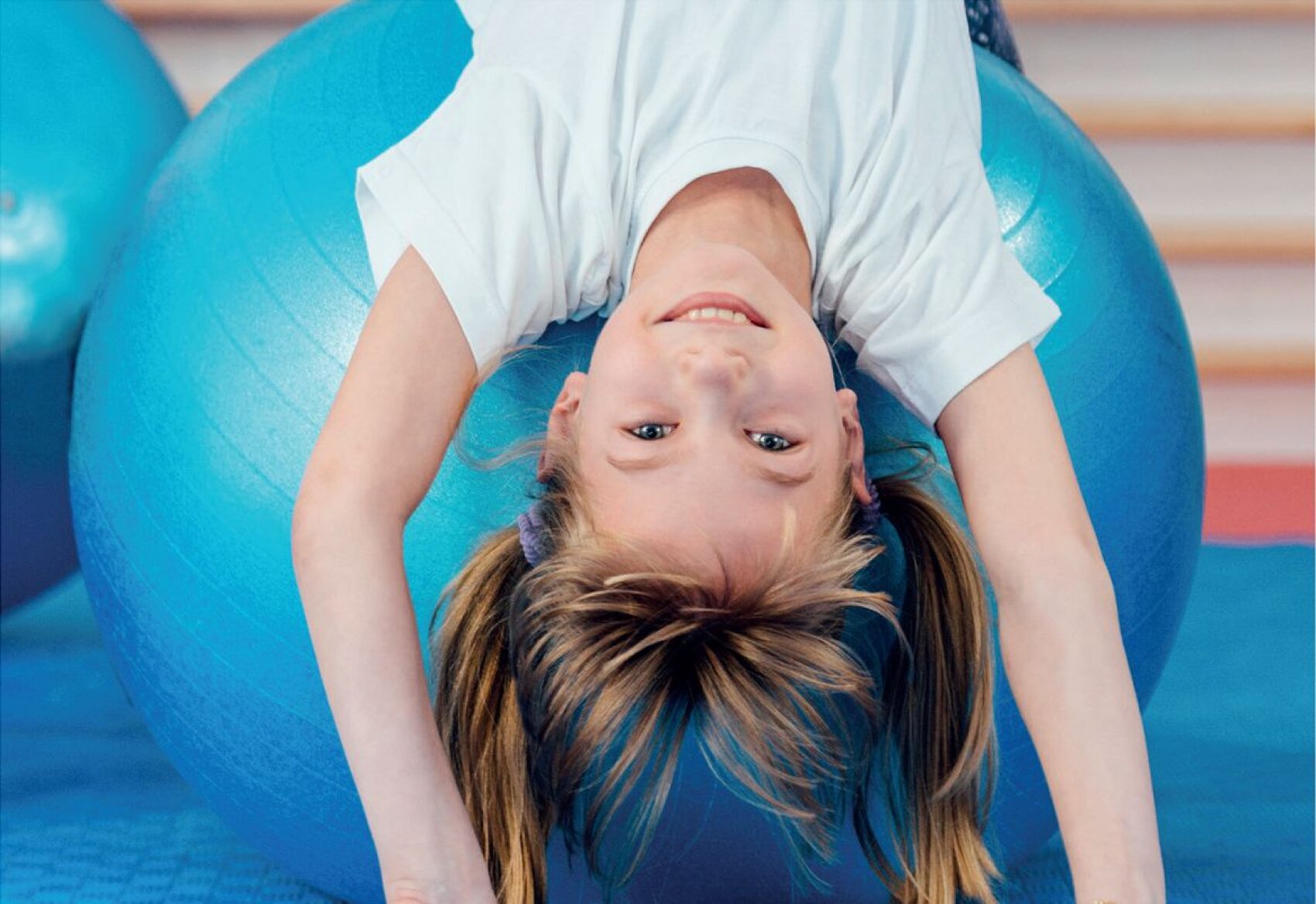 Kind ohne Sehhilfe, kopfüber auf einem Gymnastikball